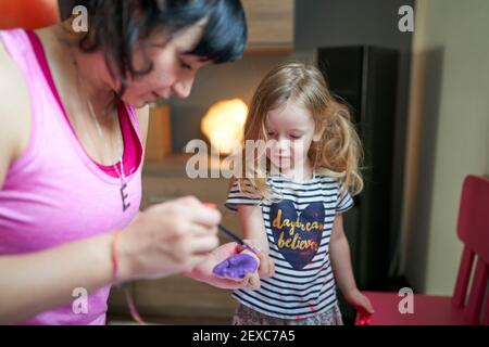 Mutter malt auf den Handflächen der Tochter mit Aquarellen Stockfoto