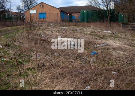 Fliegen kippte Müll und Hausmüll illegal auf die gedumpt Rand des lokalen Waldes in Großbritannien.EIN geschlossenes SureStart Center Kann im Hintergrund gesehen werden Stockfoto
