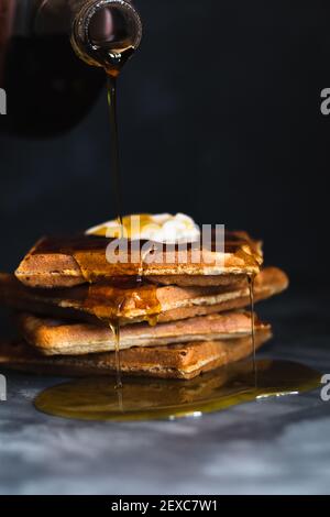 Ahornsirup Gießen auf einen Stapel von Waffeln gekrönt mit Butter Stockfoto