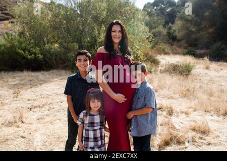 Schwangere Mutter posiert mit drei Kindern im Feld in San Diego Stockfoto