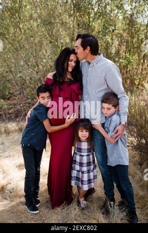 Ehemann küssend werdende Mutter mit Kindern im Feld in San Diego Stockfoto