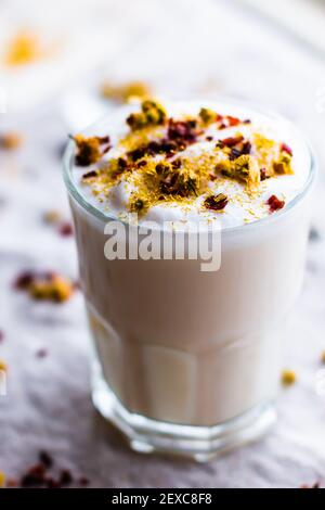 Rosa Tee Latte in Glas mit schaumigem Milch, Hagebutten und Kamille gekrönt Stockfoto