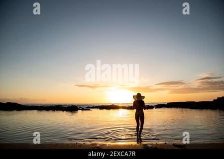 Eine Frau steht in der flachen trägt einen Hut an Sonnenuntergang Stockfoto