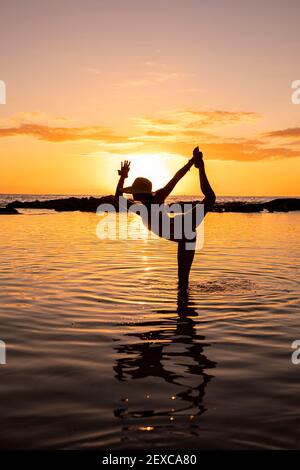 Weiblich in Tänzerin Pose im seichten Wasser vor Sonnenuntergang Stockfoto