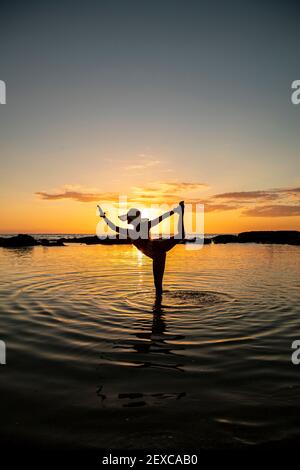 Weiblich in Tänzerin Pose im seichten Wasser vor Sonnenuntergang Stockfoto