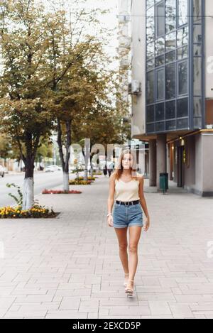 Sommer sonnig Lifestyle Mode Porträt von jungen stilvollen Hipster Frau zu Fuß auf der Straße, tragen niedlichen trendigen Outfit, lächelnd genießen ihre Wochenenden. Stockfoto