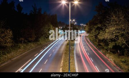 Eine lange Aufnahme einer vierspurigen Straße bei Nacht mit leuchtenden Fahrzeuglampen Stockfoto
