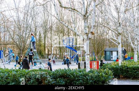 Kinder, die an einem Winternachmittag während der dritten Coronavirus-Sperre auf einem lokalen Spielplatz spielen, Islington, London, Großbritannien Stockfoto