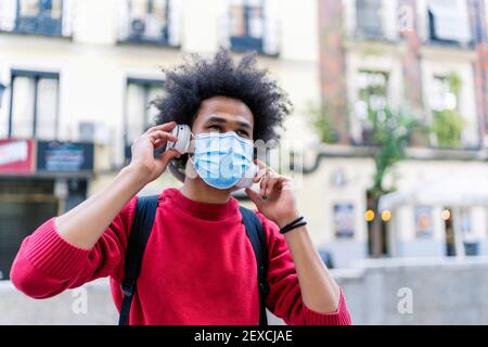 Junger Mann mit Afro-Haaren, der Musik von ihm hört Smartphone Stockfoto