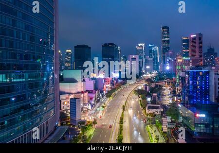 Luftaufnahme des sich schnell bewegenden Verkehrs auf der mehrspurigen Autobahn durch das Stadtzentrum mit Wolkenkratzern Autobahn durch die Innenstadt von Jakarta, Indonesien Stockfoto
