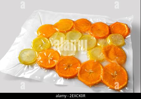 Zitronen- und Orangenscheiben vakuumverpackt für Sous Vide versiegelt Kochen auf weißem Hintergrund Stockfoto
