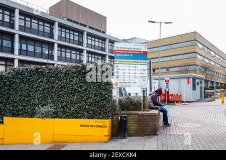 Ein Mann wartet vor dem Eingang der Unfall- und Notaufnahme des Whittington Hospital auf Highgate Hill, Islington, London, Großbritannien Stockfoto