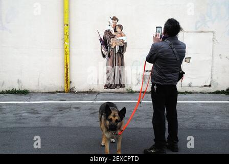 Anti-Vaxer vandalisieren Straßenkünstler Arbeit. Padua, Italien. Der Schriftsteller Evyrein malte kürzlich zwei Bilder des Heiligen Antonius, der eine große Pfizer-Impfspritze statt der Lilie an zwei verschiedenen Wänden in der Stadt hielt, um die Anti-Covid-Impfkampagne 19 zu fördern. Anti-vax-Leute kritisierten die Initiative heftig, ruinierten die Murales und drohten Evyrein in den sozialen Medien zu töten. Stockfoto