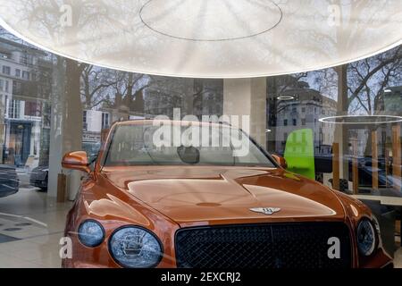 Während der Schließung nicht wichtiger Geschäfte während der Coronavirus-Pandemie durch ein Fenster gesehen, befindet sich am 4th. März 2021 im Jack Barclay Showroom in Mayfair in London, England, ein Luxus-Bentley-Fahrzeug. Stockfoto