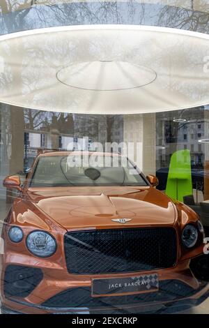 Während der Schließung nicht wichtiger Geschäfte während der Coronavirus-Pandemie durch ein Fenster gesehen, befindet sich am 4th. März 2021 im Jack Barclay Showroom in Mayfair in London, England, ein Luxus-Bentley-Fahrzeug. Stockfoto