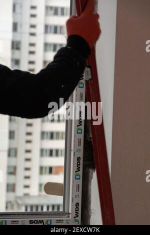 Tiraspol, Moldawien - 2. März 2021: Installation von Fenstern. Der Bauherr installiert eine pvc-Fenstermarke WDS in der Wohnung eines Mehrfamilienhauses. Stockfoto