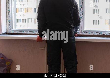 Tiraspol, Moldawien - 2. März 2021: Installation von Fenstern. Der Bauherr installiert eine Kunststoff-Fensterbank in der Wohnung auf dem Schaum. Stockfoto