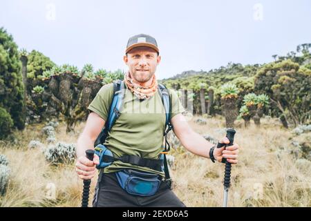 Backpacker-Mann-Portrait bei einer Wanderung mit Wanderstöcken auf der Umbwe-Route im Wald zum Kilimanjaro-Berg. Aktive Klettern Menschen und Stockfoto