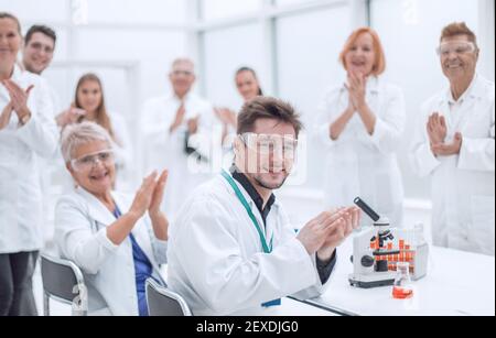 Eine Gruppe junger Wissenschaftler gratuliert ihrem Kollegen mit Applaus Stockfoto