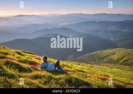 Frau auf dem Berggipfel mit grünem Gras und rosa Blumen Stockfoto