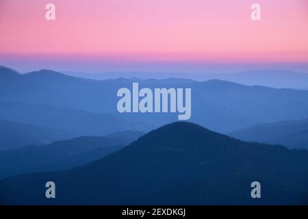 Bergrücken im Nebel bei Sonnenuntergang im Herbst. Wunderschöne Landschaft Stockfoto