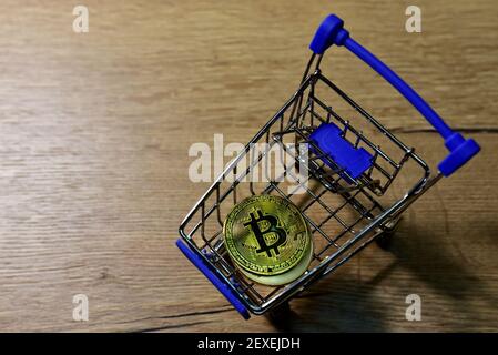 Warenkorb mit Bitcoin Gold Krypto Münzen auf Holz Hintergrund. BTC Kryptowährung Anlagekonzept in Mini-Shopping-Trolley. Blockchain und Financi Stockfoto