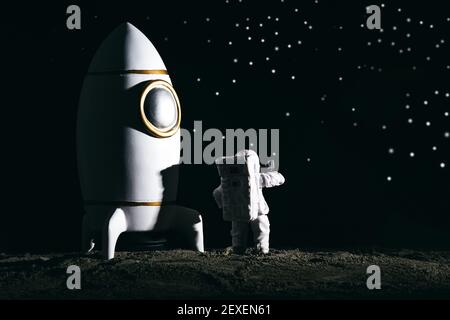 Ein Astronaut Miniaturspielzeug neben einer Rakete auf dem mond vor Bokeh Hintergrund Stockfoto