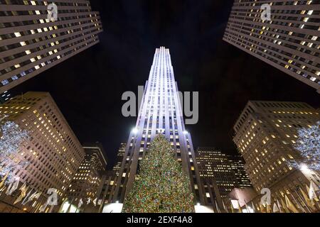 Weihnachtsbaum leuchtet im Rockefeller Center zwischen dem Wolkenkratzer in Midtown Manhattan in der Nacht in New York City NY USA. Stockfoto