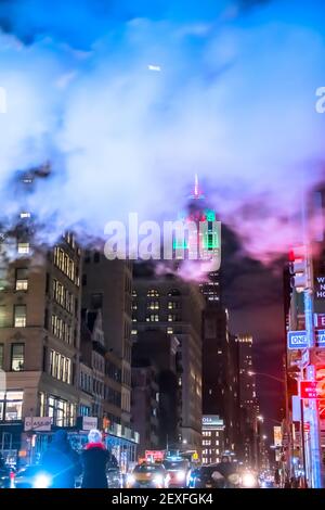 Das Empire State Building leuchtet während der Weihnachtsfeiertage in New York City unter den Gebäuden von Midtown Manhattan. Stockfoto