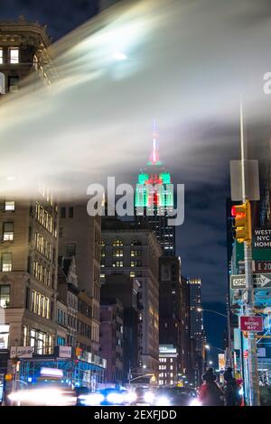 Das Empire State Building leuchtet während der Weihnachtsfeiertage in New York City unter den Gebäuden von Midtown Manhattan. Stockfoto