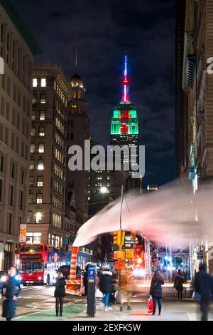 Das Empire State Building leuchtet während der Weihnachtsfeiertage in New York City unter den Gebäuden von Midtown Manhattan. Stockfoto