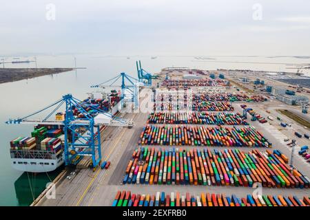 Containerhafen mit großem Schiff, das mit Portalkran beladen und entladen wird. Internationaler Versand und globaler Güterverkehr und Handel. Antenne V Stockfoto