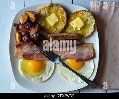 Frühstücksteller bestehend aus zwei Eiern, Speck und englischem Muffin Stockfoto