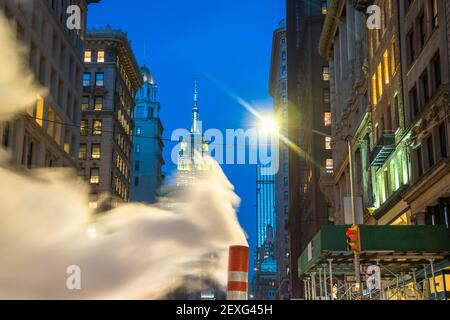 Das Empire State Building leuchtet während der Weihnachtsfeiertage in New York City zwischen den Gebäuden von Midtown Manhattan. Stockfoto