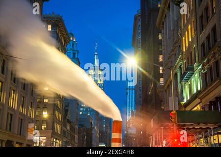 Das Empire State Building leuchtet während der Weihnachtsfeiertage in New York City zwischen den Gebäuden von Midtown Manhattan. Stockfoto