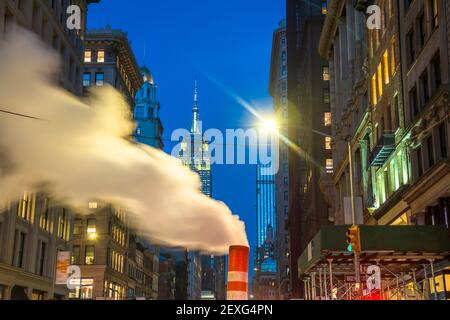 Das Empire State Building leuchtet während der Weihnachtsfeiertage in New York City zwischen den Gebäuden von Midtown Manhattan. Stockfoto