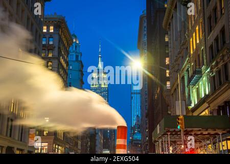 Das Empire State Building leuchtet während der Weihnachtsfeiertage in New York City zwischen den Gebäuden von Midtown Manhattan. Stockfoto