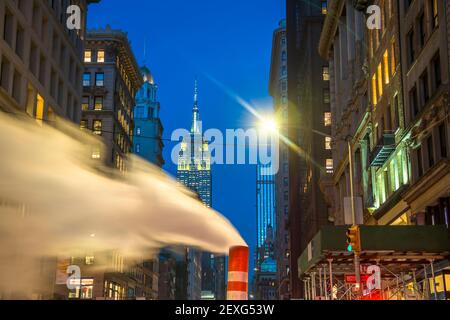 Das Empire State Building leuchtet während der Weihnachtsfeiertage in New York City zwischen den Gebäuden von Midtown Manhattan. Stockfoto