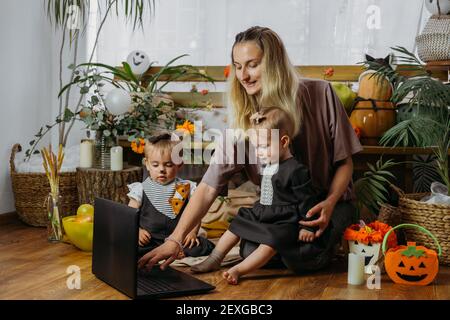 Feiertage in der Zeit von COVID. Glückliche Familie, Mutter und Baby feiern Halloween über das Internet in neuer normaler, Pandemic Zeit. Online-Feiertagsfeier Stockfoto