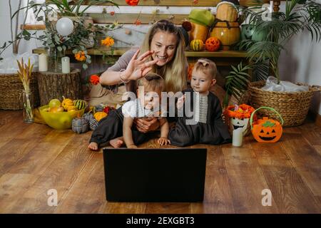 Feiertage in der Zeit von COVID. Glückliche Familie, Mutter und Baby feiern Halloween über das Internet in neuer normaler, Pandemic Zeit. Online-Feiertagsfeier Stockfoto