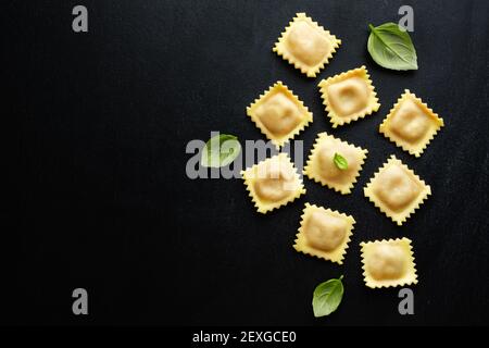 Leckere klassische italienische Ravioli mit Basilikum auf dunklem Hintergrund. Draufsicht. Stockfoto