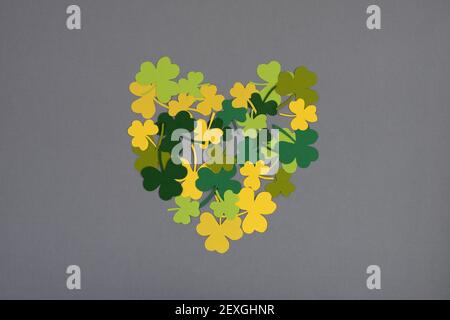 St. Patricks Day. Herzform von Kleeblättern auf grauem Hintergrund. Flach liegend, Draufsicht. Stockfoto