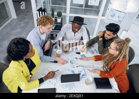 Multirassische Studenten, Designer oder IT-Spezialisten, die mit Grafiken und Diagrammen arbeiten Stockfoto