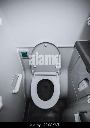 Eine vertikale Weitwinkelansicht eines Teils des Innenraums Und eine Toilettenschüssel mit dem Deckel im Innenbereich geöffnet Ein winziger Toilettenraum an Bord eines Passagierflugzeugs i Stockfoto