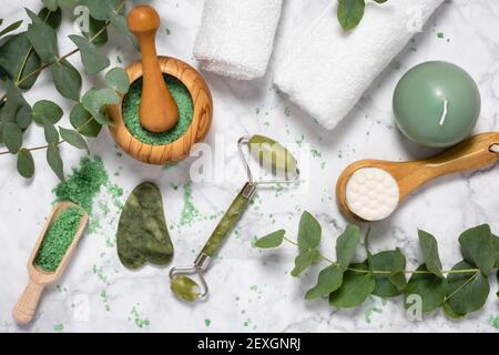 Natürliche Wellness und Anti-Aging-Pflege mit Beauty-Jade-Roller, Gua Sha , Badesalz und Eukalyptus Zweig auf Marmor Hintergrund. Spa, Gesichtsmassage Stockfoto