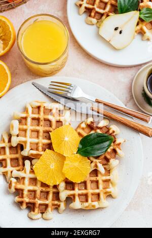 Hausgemachte Waffeln auf einem hellrosa Hintergrund. Orangensaft. Obst Stockfoto