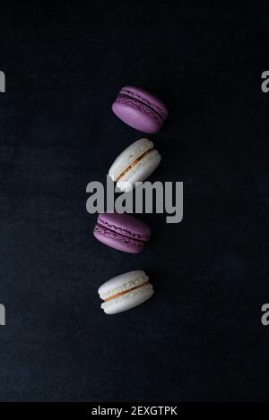 Bunte Makronen in Aktion auf dunklem Hintergrund Stockfoto