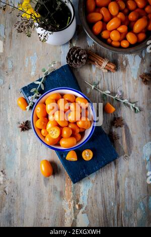 Draufsicht auf frische Kumquats in der Platte auf dem natürlichen Holzhintergrund. Cumquat oder Kumquat. Stockfoto