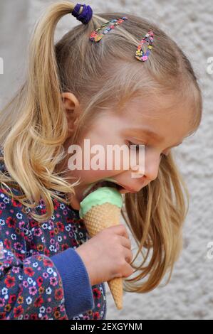 Nette kleine blonde Mädchen essen Eis Stockfoto