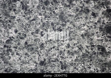 Dunkelgrauer Granit mit kleinen Einschlüssen in weißer Farbe, Nahaufnahme von polierter, flacher Oberfläche aus Naturstein. Hintergrund, Muster, Textur. Stockfoto